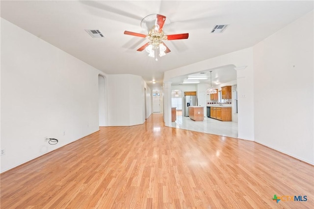 unfurnished living room featuring decorative columns, ceiling fan, and light hardwood / wood-style floors