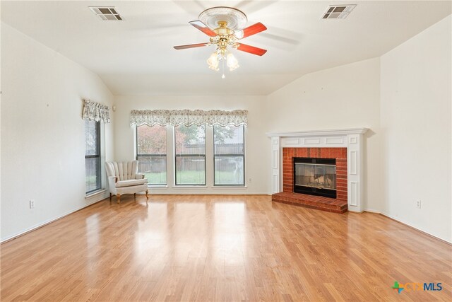 unfurnished living room featuring light wood-type flooring, vaulted ceiling, and a brick fireplace