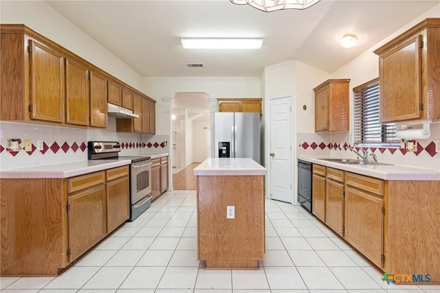 kitchen with stainless steel appliances, a center island, light tile patterned floors, and backsplash