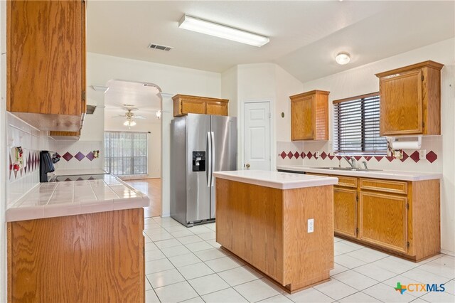 kitchen with stainless steel fridge with ice dispenser, sink, backsplash, and a center island