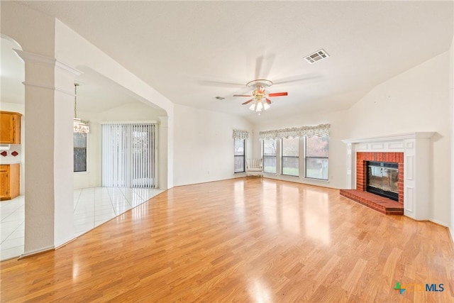 unfurnished living room featuring vaulted ceiling, a brick fireplace, light hardwood / wood-style floors, and ceiling fan