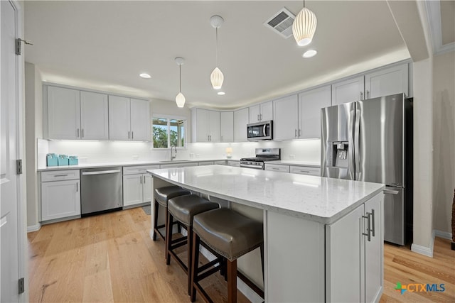 324 Brenham Pass, Georgetown, TX 78633 - kitchen with visible vents, a center island, a sink, light wood finished floors, and appliances with stainless steel finishes