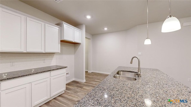 kitchen with sink, dark stone countertops, white cabinets, and decorative light fixtures