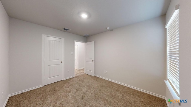 unfurnished bedroom featuring carpet flooring and multiple windows