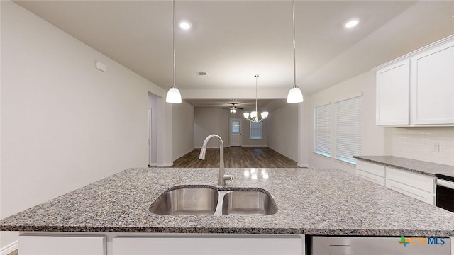 kitchen featuring sink, light stone countertops, a kitchen island with sink, and hanging light fixtures