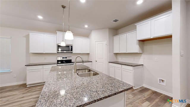 kitchen with pendant lighting, appliances with stainless steel finishes, sink, and white cabinets