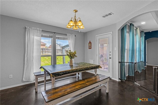 dining area with visible vents, concrete floors, arched walkways, a notable chandelier, and a textured ceiling