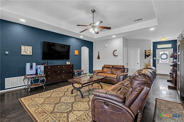 living room featuring arched walkways, finished concrete floors, and visible vents