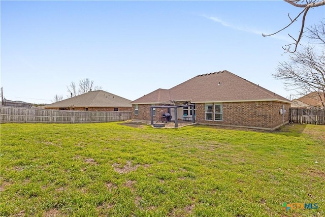 back of property with a yard, brick siding, a fenced backyard, and a patio area