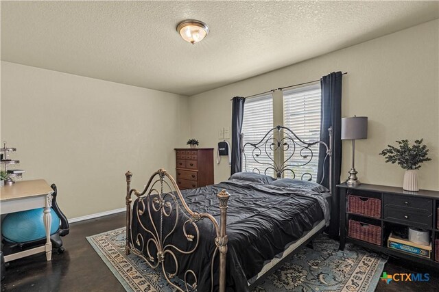 bedroom with baseboards, a textured ceiling, and finished concrete floors