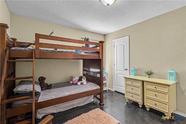 bedroom with finished concrete flooring, a textured wall, and a textured ceiling