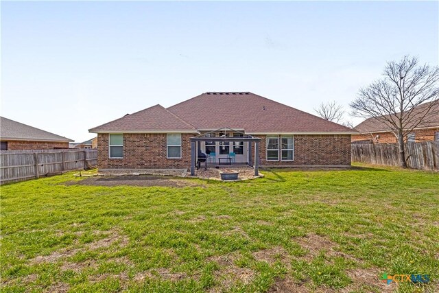 rear view of house with brick siding, a fenced backyard, and a yard