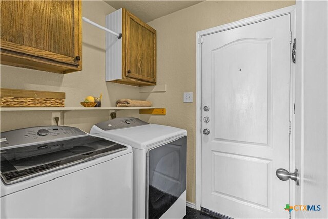 washroom featuring cabinet space and washer and clothes dryer