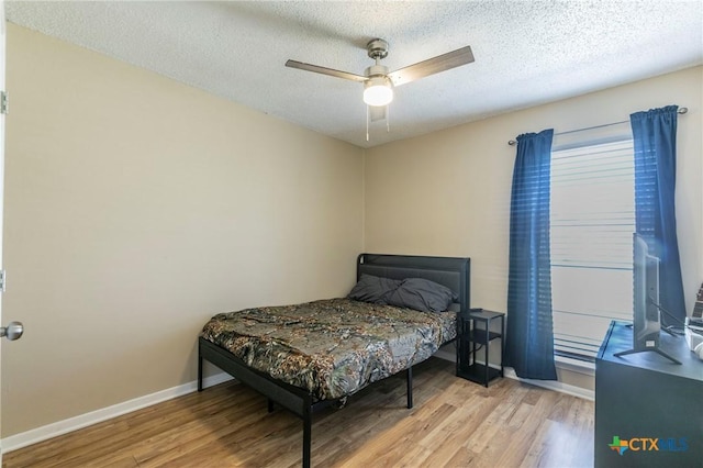 bedroom featuring a textured ceiling, light wood-style flooring, and baseboards