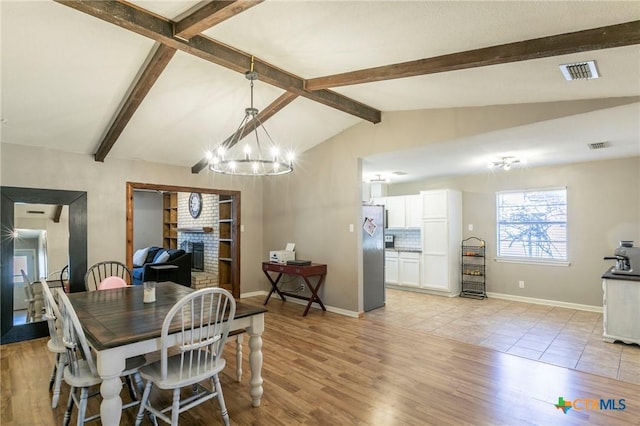 dining area featuring visible vents, lofted ceiling with beams, light wood-style floors, a brick fireplace, and baseboards