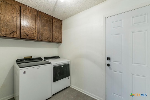 laundry area with cabinet space, baseboards, wood finished floors, a textured ceiling, and washer and dryer