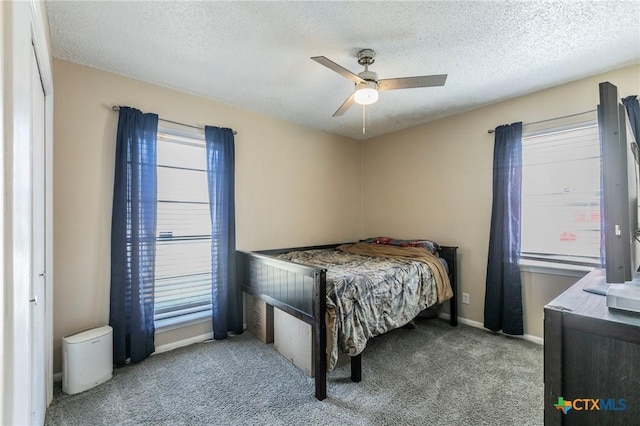 bedroom featuring ceiling fan, a textured ceiling, baseboards, and carpet flooring