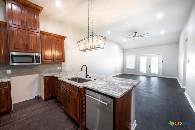 kitchen featuring stainless steel appliances, sink, kitchen peninsula, tasteful backsplash, and hanging light fixtures