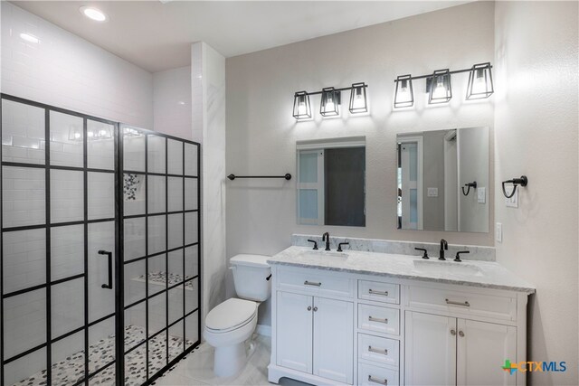 bathroom with vanity, toilet, and a tile shower