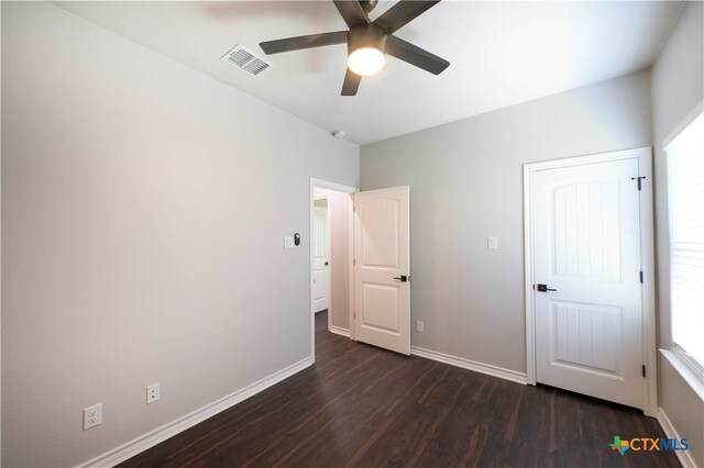 unfurnished bedroom featuring dark hardwood / wood-style floors, ceiling fan, and multiple windows