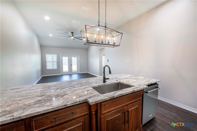 kitchen with ceiling fan with notable chandelier, dark wood-type flooring, sink, light stone countertops, and decorative light fixtures