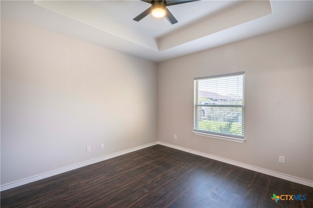 empty room with dark wood-type flooring, ceiling fan, and a raised ceiling