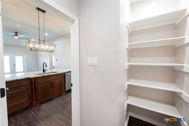 bar featuring sink, ceiling fan, decorative light fixtures, dishwasher, and dark hardwood / wood-style flooring