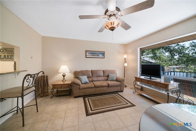 living room with a textured ceiling, ceiling fan, and light tile patterned flooring