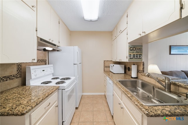 kitchen with wooden walls, white cabinetry, white appliances, and sink