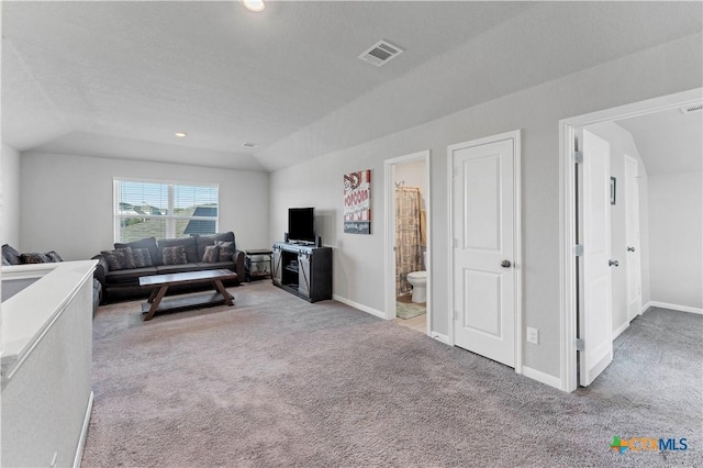 living room featuring lofted ceiling, light carpet, and a textured ceiling