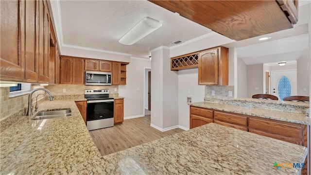 kitchen featuring sink, light hardwood / wood-style flooring, light stone countertops, tasteful backsplash, and stainless steel appliances