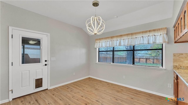 unfurnished dining area with light hardwood / wood-style floors, an inviting chandelier, and lofted ceiling