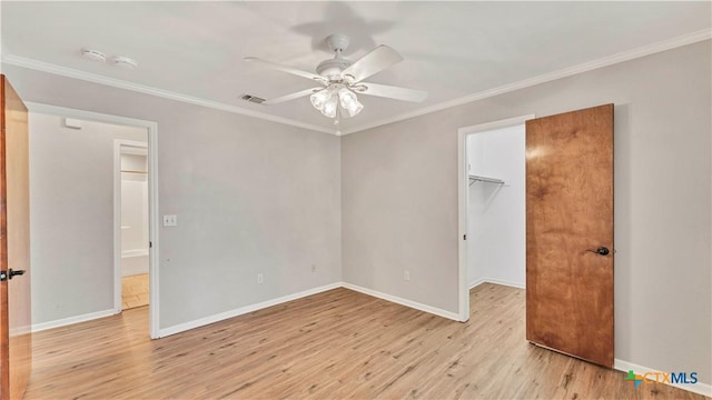 unfurnished bedroom featuring a walk in closet, ornamental molding, ceiling fan, light hardwood / wood-style flooring, and a closet