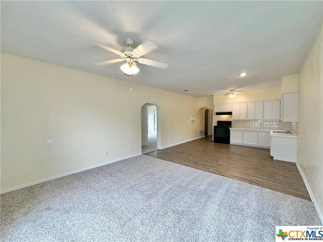 unfurnished living room with hardwood / wood-style floors, ceiling fan, a textured ceiling, and sink