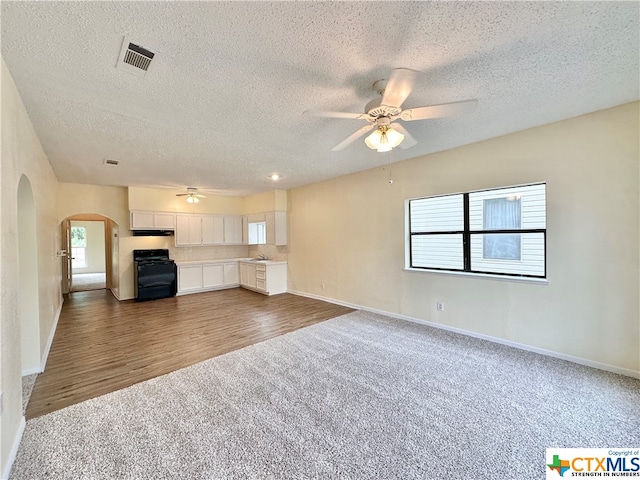 unfurnished living room with sink, dark carpet, a textured ceiling, and ceiling fan