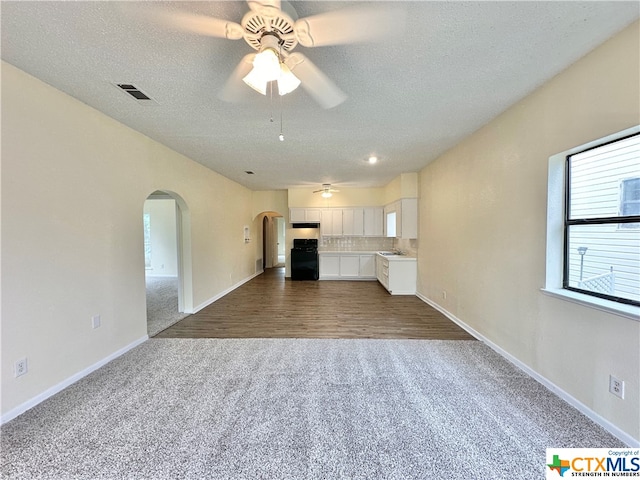 unfurnished living room with ceiling fan, carpet flooring, sink, and a textured ceiling