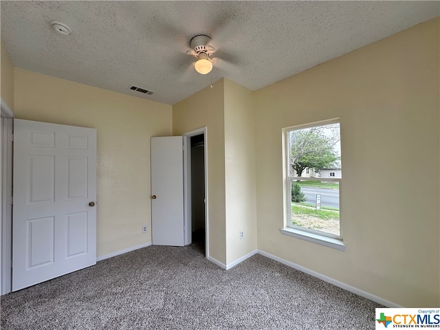 unfurnished bedroom with ceiling fan, carpet flooring, and a textured ceiling