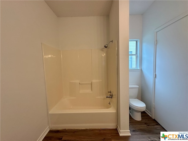 bathroom featuring hardwood / wood-style flooring, toilet, and bathtub / shower combination