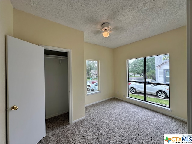 unfurnished bedroom featuring ceiling fan, carpet floors, and a textured ceiling