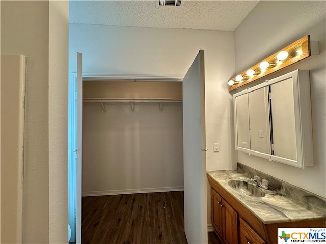 bathroom with wood-type flooring, vanity, and a textured ceiling