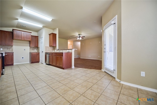 kitchen with kitchen peninsula, ceiling fan, light tile patterned floors, and decorative backsplash