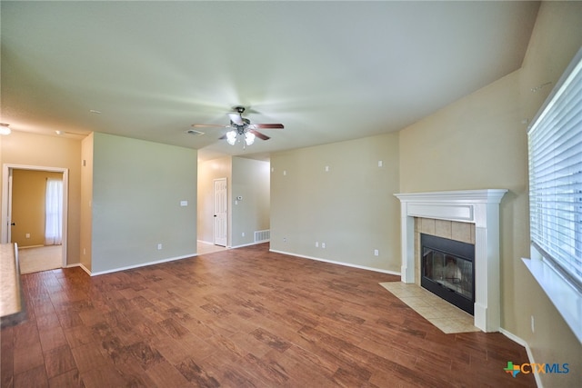 unfurnished living room featuring hardwood / wood-style flooring, ceiling fan, and a tile fireplace