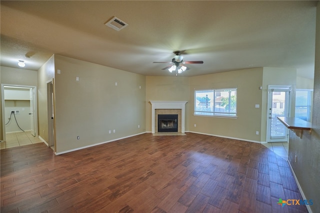 unfurnished living room featuring wood-type flooring, ceiling fan, and a tile fireplace