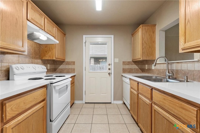kitchen with a sink, white appliances, light tile patterned floors, tasteful backsplash, and under cabinet range hood
