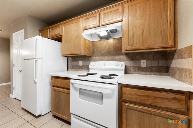 kitchen with white appliances, under cabinet range hood, light tile patterned floors, and tasteful backsplash