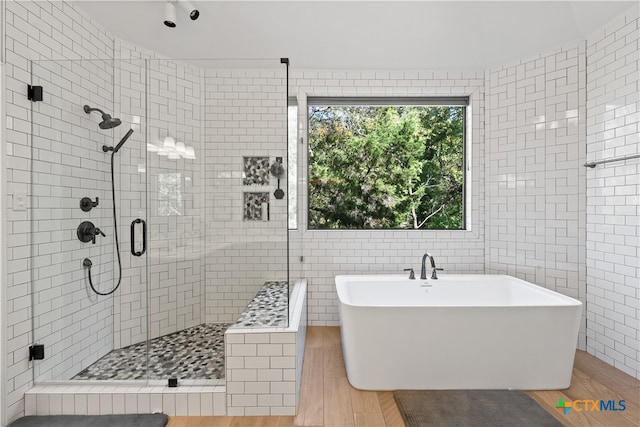 bathroom featuring tile walls, wood-type flooring, and plus walk in shower