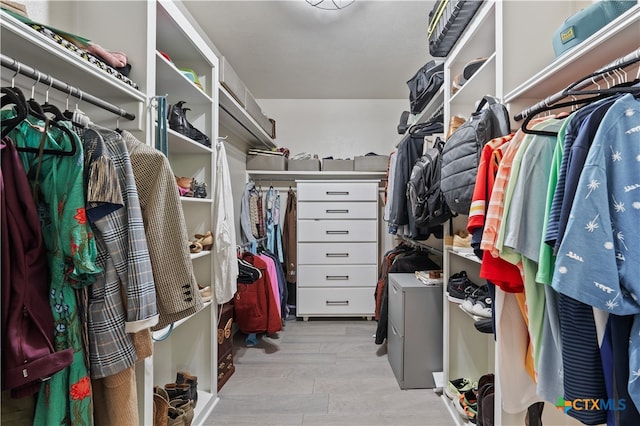 walk in closet with separate washer and dryer and light hardwood / wood-style floors