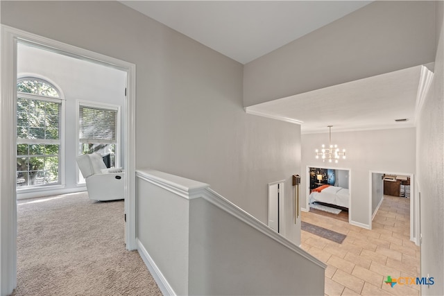 hall with light carpet, crown molding, and an inviting chandelier