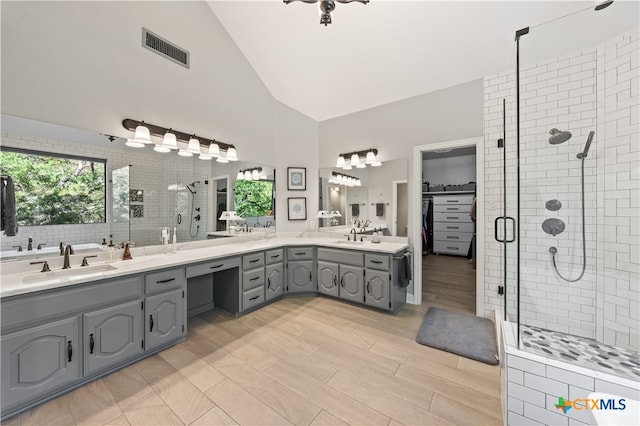 bathroom featuring high vaulted ceiling, vanity, hardwood / wood-style floors, and a shower with shower door