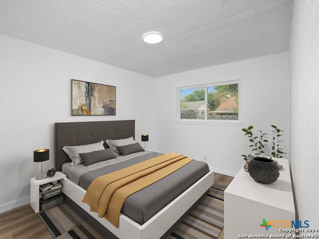 bedroom with dark hardwood / wood-style floors and a textured ceiling